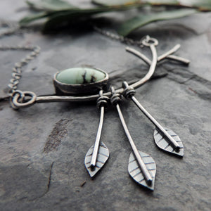 pendant with three leaves hanging from tree limb and gemstone