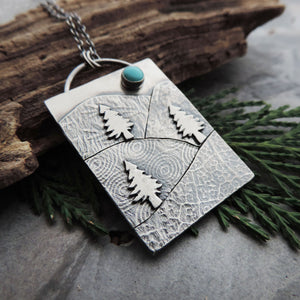 silver pendant with textured mountains and turquoise stone